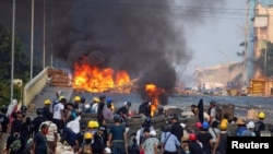 Manifestantes contra el golpe militar se protegen detrás de una barricada en choques con las fuerzas de seguridad en un puente de Rangún, Myanmar, el 16 de marzo de 2021.
