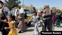 Mujeres con sus hijos intentan entrar en el aeropuerto internacional Hamid Karzai de Kabul, lunes 16 de agosto de 2021.