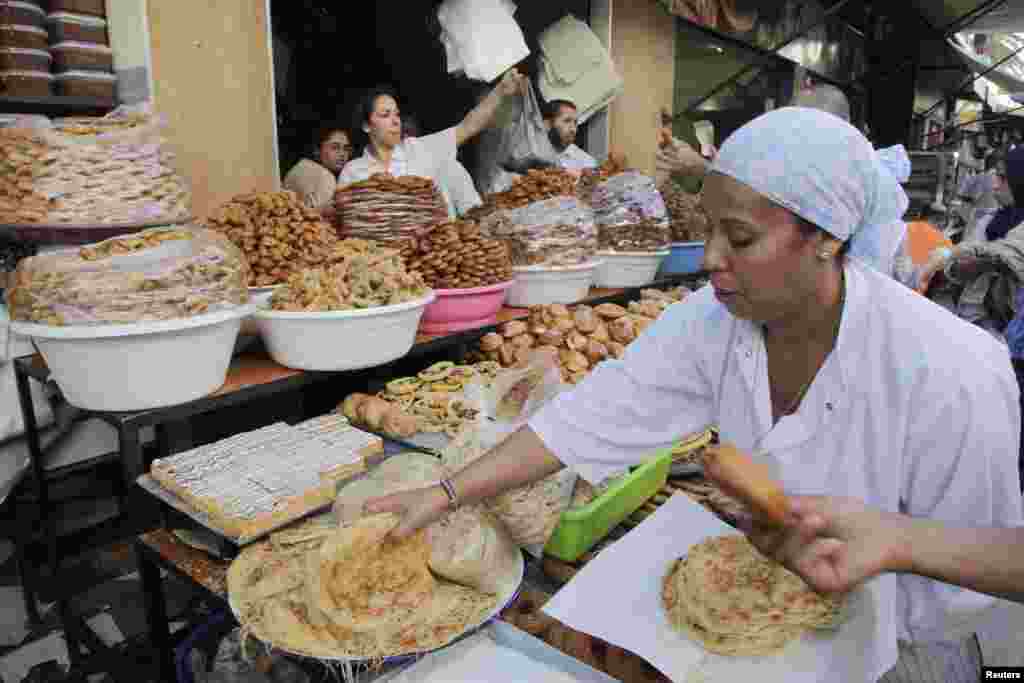 A vendor sells traditional cakes of fried honey and flour pastries to customers ahead of Ramadan in Rabat, Morocco, July 8, 2013.