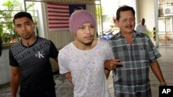 Wee Meng Chee (tengah), rapper Malaysia yang dikenal dengan nama panggung Namewee, dikawal polisi berpakaian preman di pengadilan di Penang (22/8). (AP/Gary Chuah)