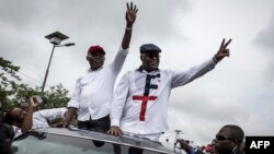 Félix Tshisekedi (à droite), leader de l'Union pour la démocratie et le progrès social (UDPS) et son allié de l'Union pour la nation congolaise (UNC), Vital Kamerhe (à gauche), saluent leurs partisans après leur retour à Kinshasa, le 27 novembre 2018.