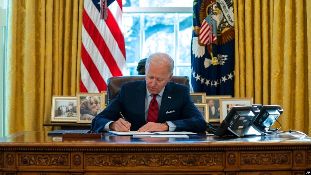 FILE - President Joe Biden signs a series of executive orders on health care, in the Oval Office of the White House, Jan. 28, 2021.