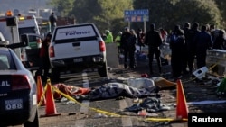 FILE - Police officers and rescue personnel stand near the bodies of people who were killed in a car crash on the outskirts of Puebla, Mexico, Dec. 12, 2017.