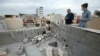 People stand next to a damaged roof after a rocket attack on U.S.-led forces in and near Irbil International Airport in Irbil, Iraq, Feb. 16, 2021.