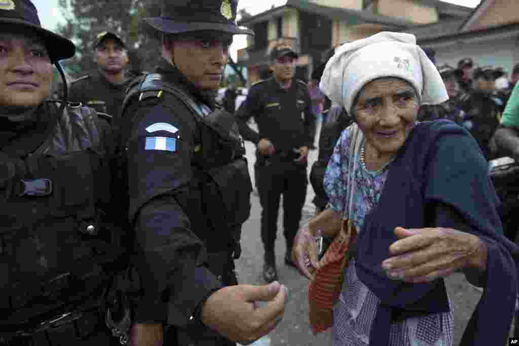 An elderly Honduran migrant woman talks with Guatemalan police who temporarily block the road to keep her and her caravan from advancing, in Esquipulas, Guatemala, Oct. 15, 2018.