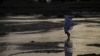FILE - A woman walks across a river bed in Jalingo, Nigeria.