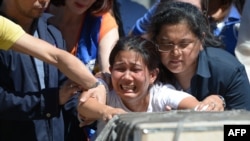 Jessica (tengah), saudara perempuan TKW asal Filipina, Joanna Demafelis, yang jenazahnya ditemukan di dalam lemari pendingin di Kuwait, menangis di depan peti jenazah yang berisi tubuh saudaranya, tak lama setelah tiba di bandara internasional Manila, 16 Februari 2018. (Foto: dok).
