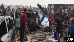 ARCHIVO - Palestinos se reúnen en el lugar de un ataque israelí contra un campamento para desplazados internos en Rafah el 27 de mayo de 2024.