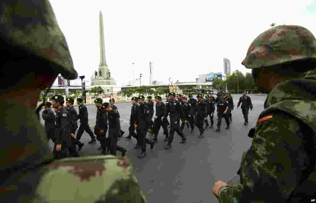 Soldiers watch as police officers are reinforced to prevent an anti-coup demonstration at the Victory Monument in Bangkok, May 29, 2014.