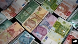 FILE - Turkish liras, center, featuring images of Turkish Republic founder Mustafa Kemal Ataturk, among other foreign currency, Istanbul, June 8, 2015.