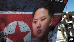 North Korean defector Park Sang Hak, right, carries a poster showing North Korean leader Kim Jong-Un during anti-Pyongyangrally near Unification Observation Post, Paju, South Korea, Oct. 4, 2013.