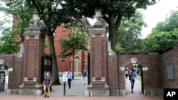 FILE - In this Aug. 13, 2019, file photo, pedestrians walk through the gates of Harvard Yard at Harvard University in Cambridge, Mass. Harvard and the Massachusetts Institute of Technology filed a federal lawsuit Wednesday, July 8, 2020, challenging the T