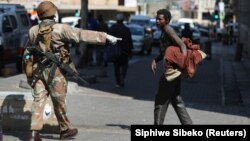 Un membre des Forces de défense nationale sud-africaines demande à un sans-abri de déguerpir, à Johannesburg, Afrique du Sud, le 27 mars 2020. (Photo: REUTERS/Siphiwe Sibeko)