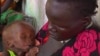 In this photo taken from Video provided by Associated Press on Tuesday, May 13, 2014, a malnourished child is fed by her mother, in a Medecins Sans Frontiers (Doctors Without Borders) hospital, in Leer, South Sudan. Bodies stuffed in wells. Houses burn