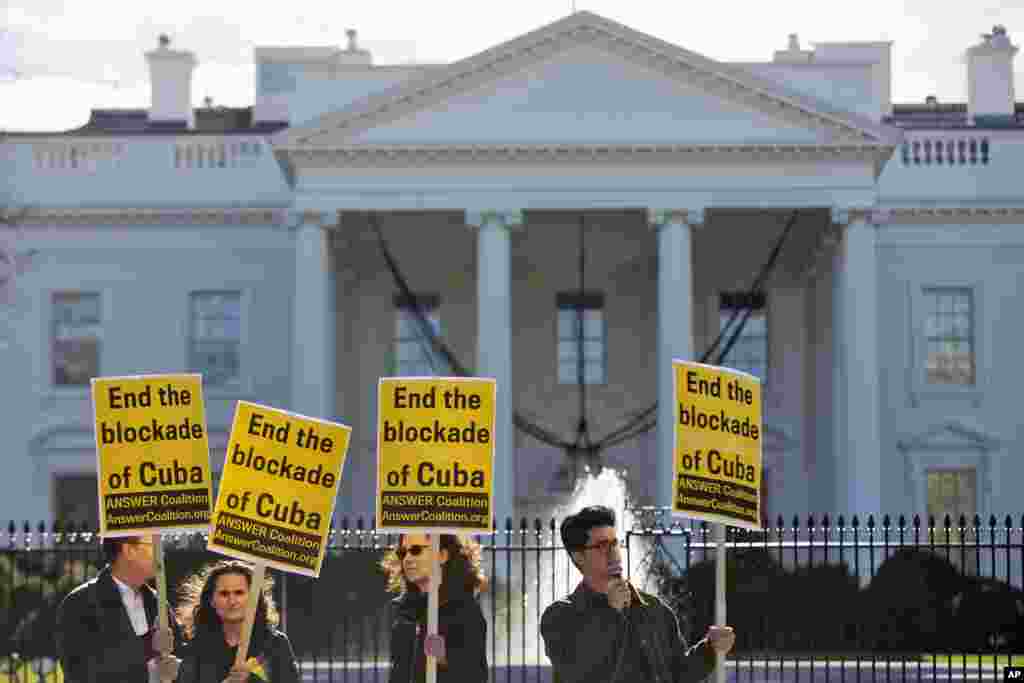 People from the ANSWER Coalition (Act Now to Stop War and End Racism) hold signs urging the U.S. to "End the blockade of Cuba," during a demonstration as President Barack Obama announced a change in U.S. policy with Cuba, White House, Dec. 17, 2014.