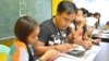 Alvin Balenton, flanked by his two youngest children, attends a class for single fathers coping with life apart from their wives who work overseas, Mabalacat, Pampanga Province, Philippines, Oct. 29, 2014. (VOA / S. Orendain)