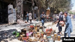 Para pemilik toko Afghanistan berupaya menyelamatkan sisa-sisa barang dagangan dari toko-toko yang terbakar setelah serangan Taliban ke Kota Ghazni, Afghanistan, 14 Agustus 2018.