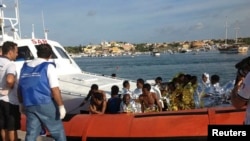 Migran yang berhasil diselamatkan dari tenggelamnya kapal di lepas pantai Italia, tiba di pelabuhan Lampedusa dengan kapal pengawal pantai (3/10).
