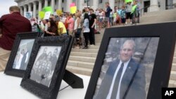 FILE - Family photographs of Joshua Holt, an American jailed in Venezuela, are part of a rally at the Utah State Capitol, July 30, 2016, in Salt Lake City. Holt was arrested on suspicion of weapons charges after he traveled to Venezuela on a tourist visa to marry a fellow Mormon he met on the internet.
