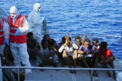 FILE - Migrants are evacuated by Italian Coast guards from the Open Arms Spanish humanitarian boat at the coasts of the Sicilian island of Lampedusa, southern Italy, Aug. 17, 2019.