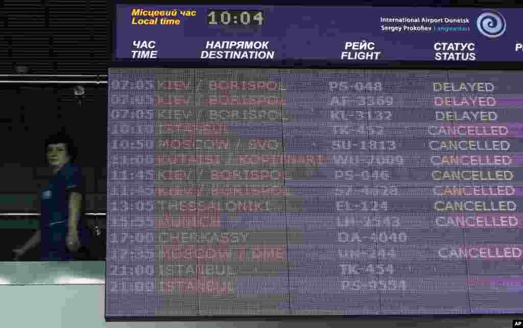 A worker walks past an information board displaying flight delays and cancellations at the international airport in Donetsk, May 6, 2014.