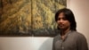 Nov Cheanick, a Battambang-based painter, is pictured in front of his own painting at TINI café in Phnom Penh, Cambodia, September 27, 2017. (Tum Malis/VOA Khmer)