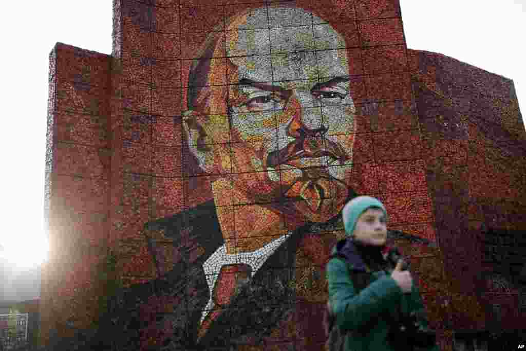 A boy pauses for photos in front of a mosaic portrait of Vladimir Lenin at the 2014 Winter Olympics, in Sochi, Russia, Feb. 20, 2014