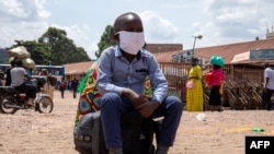 A boy sits on a bag at the old taxi park in Kampala, Uganda, on June 4, 2020, the first day of the reopening of public transport. 