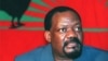 Jonas Savimbi, fotografado em data não determinada, em frente a uma bandeira da UNITA, com o lendário galo negro. Savimbi foi morto há 9 anos pelas forças governamentais, na província do Moxico.