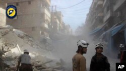 In this picture provided by the Syrian Civil Defense group known as the White Helmets, Syrian Civil Defense workers search through the rubble in rebel-held eastern Aleppo, Syria, Oct. 12, 2016. 