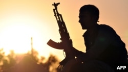 A fighter from the Kurdish People Protection Unit (YPG) is photographed at sunset in the Syrian town of Ain Issi, north of Raqqa during clashes between IS jihadists and YPG fighters, July 10, 2015. 