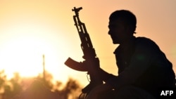 FILE - A fighter from the Kurdish People Protection Unit (YPG) waits in the Syrian town of Ain Issi, north of Raqqa, during clashes between IS group jihadists and YPG fighters, July 10, 2015. 