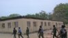 FILE - Security guards walk past a burned-out government secondary school in Chibok, Nigeria. April, 21. 2014.
