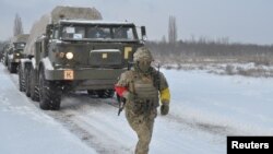 Un miembro del servicio de las Fuerzas Armadas de Ucrania corre cerca de sistemas de lanzacohetes múltiples autopropulsados durante simulacros en la región de Kherson, Ucrania, en esta foto publicada el 1 de febrero de 2022.