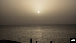 People watch the sunset while a cloud of Sahara dust hangs in the air in Havana, Cuba, on June 24, 2020. 
