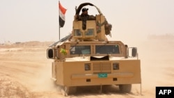 FILE - Iraqi government forces drive their armored vehicle, June 22, 2016, some 40 kilometers (25 miles) west of Qayyarah, during their operation to take the city and make it a launchpad for Mosul. 