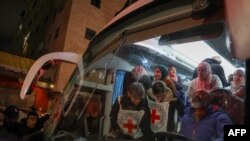 Палестински затвореници (позади) чекаат да се симнат од автобус на Црвениот крст по нивното пристигнување во окупираниот град Беитунија на Западниот Брег, на периферијата на Рамала, по нивното ослободување од Израел во раните часови на 20 јануари 2025 година.