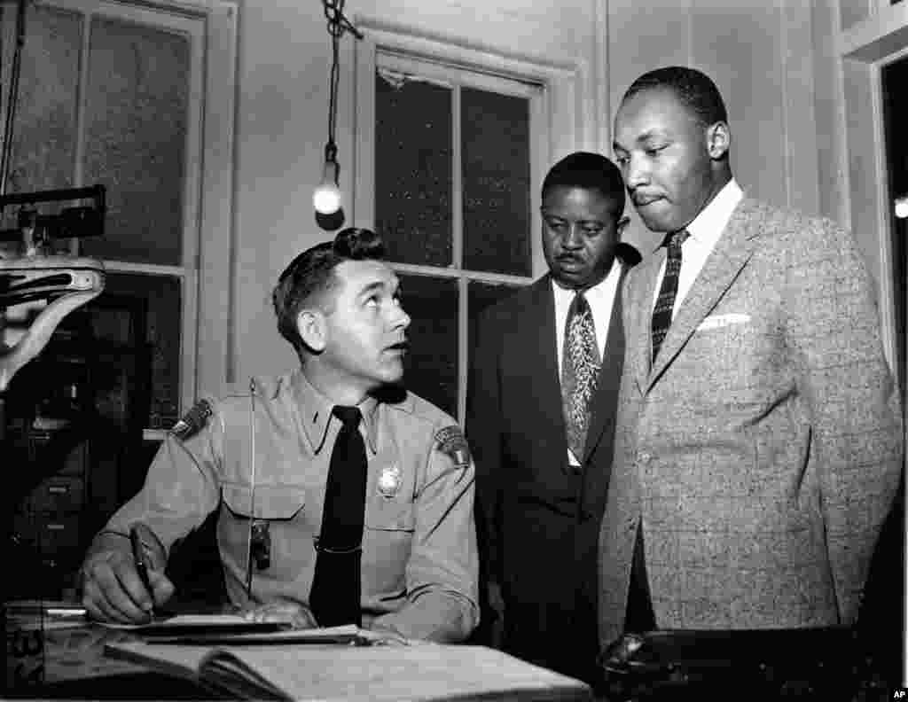 Martin Luther King, Jr., accompanied by Rev. Ralph D. Abernathy is booked by city police Lt. D.H. Lackey in Montgomery, Alabama, Feb. 23, 1956.