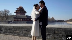 FILE - Groom Dong Yangfeng and bride Wang Sai pose for photos near the Forbidden City in Beijing on Dec. 20, 2020. 