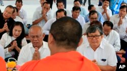 Former Vice President of opposition party Cambodia National Rescue Party (CNRP) Pol Ham, center left, prays Buddhist monks, foreground, together with his former party lawmaker Son Chhay, center right, during a Buddhist ceremony, in Phnom Penh, Cambodia, F