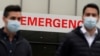 FILE - People walk past a hospital Emergency room sign during the coronavirus (COVID-19) pandemic in the Manhattan borough of New York City, New York, Dec. 4, 2020. 