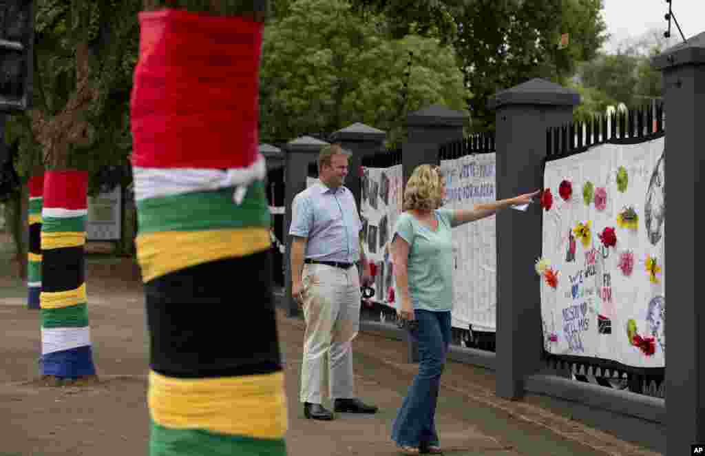 People leave messages for Nelson Mandela on a memorial site adorned with South African flags on trees, in Rosebank, an affluent district of Johannesburg, Dec. 9, 2013.