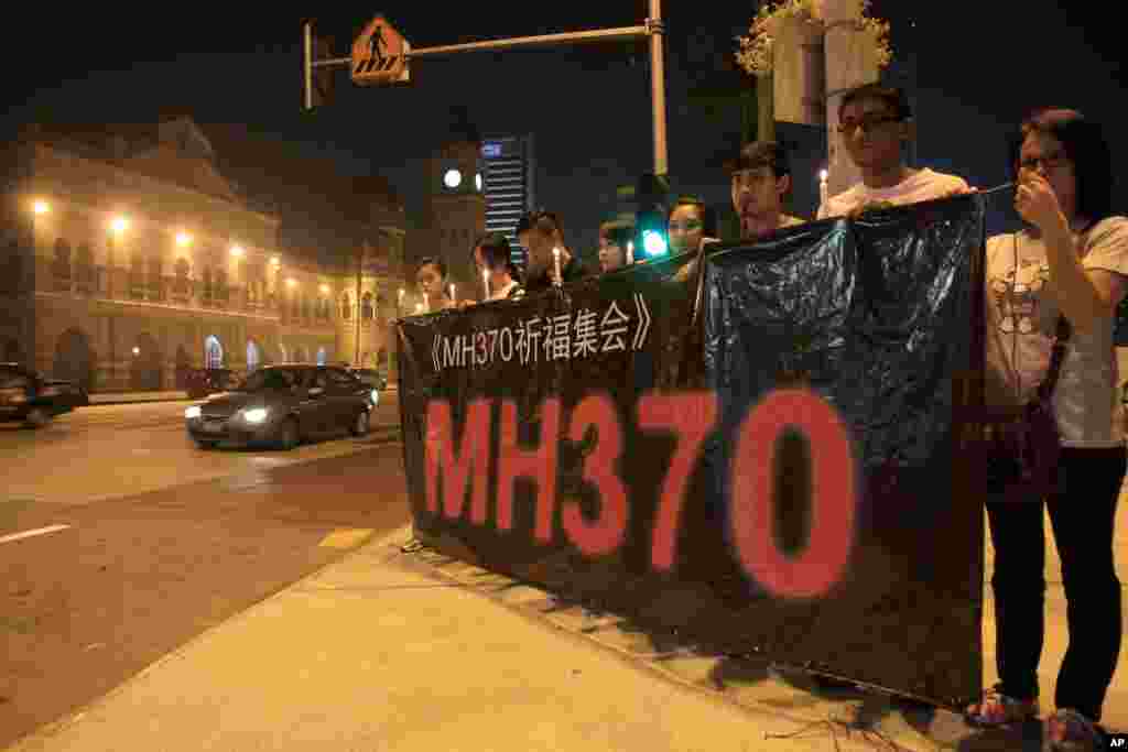 Orang-orang memegang banner dan lilin selama acara penyalaan lilin untuk penumpang pesawat Malaysia Airlines yang hilang di Kuala Lumpur, Malaysia, 10 Maret 2014. 