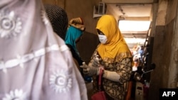 Une femme portant un masque facial et des gants comme mesure préventive contre la propagation du covid-19 à l'entrée de la mosquée de Ouagadougou, le 20 mars 2020.