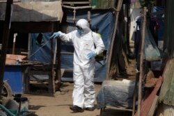 A member of the non-profit Cambodian Children's Fund sprays disinfectant to help curb the spread of the new coronavirus in the slum neighborhood of Stung Meanchey in southern Phnom Penh, Cambodia, March 24, 2020.