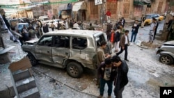 Pria Syiah dari suku Houthi berdiri di dekat mobil yang hancur di luar rumah mereka di Sanaa, Yaman (23/12).