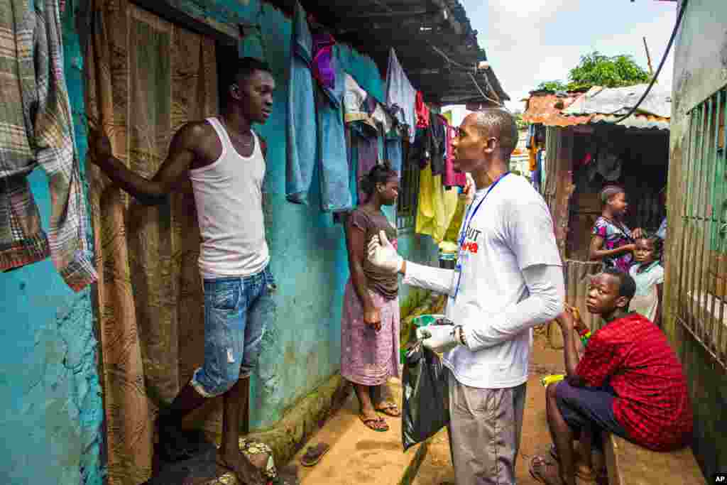 Seorang relawan medis memberikan penjelasan kepada seorang warga tentang bagaimana mencegah dan mengidentifikasii penularan virus Ebola, sambil membagikan sabun di Freetown, Sierra Leone (20/9).