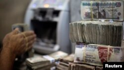 FILE - An employee counts money at an exchange office in downtown Cairo, Egypt, June 5, 2014. 