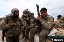 FILE - Kurdish People's Protection Units (YPG) fighters carry their weapons while riding on the back of a pick-up truck in Qamishli, Syria, March 11, 2016.