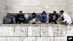 FILE - Migrants from Pakistan have their lunch in front of a railway station in Sarajevo, Bosnia, on June 19, 2018, as they wait for an opportunity to get to Croatia and Western Europe.
